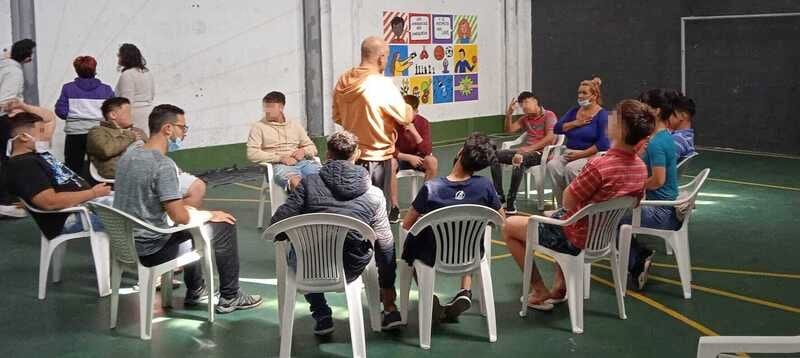 Jóvenes sentados alrededor de un hombre