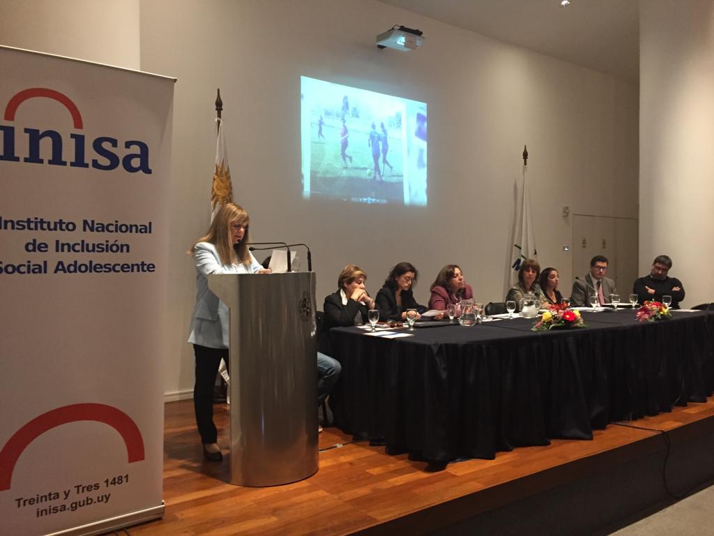 Gabriela Fulco hablando en un púlpito al lado de mesa con otras personas